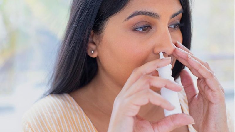 Mulher aplicando descongestionante nasal em spray