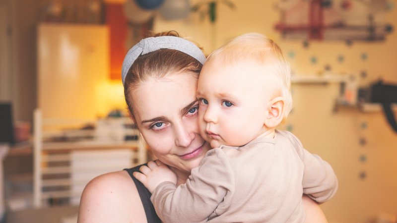 Mãe abraçando bebê rosto a rosto, com a orelha do bebê visível
